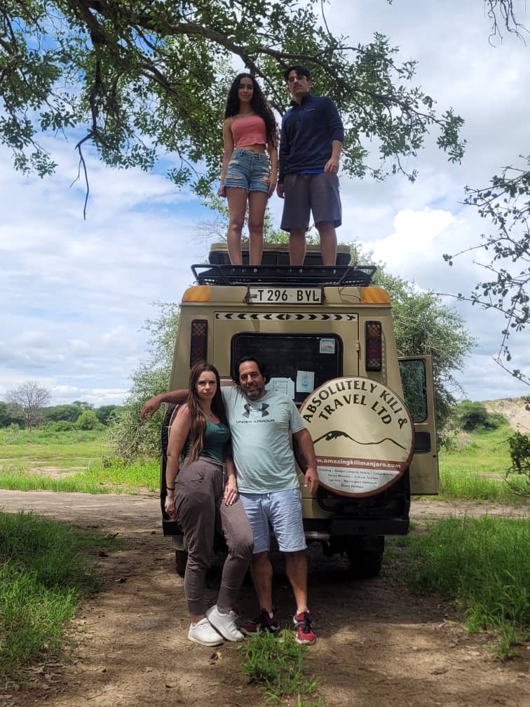 Travellers beside the Absolutely Kili & Travel safari vehicle on a Tanzania bush track